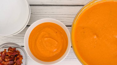 Roasted butternut squash soup recipe. To serve soup in bowls add bacon and heavy cream to garnish the meal for a better taste, close-up view, copy space clipart