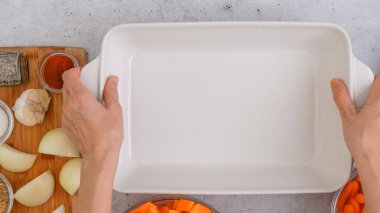 Kızarmış tereyağlı kabak çorbası tarifi. Soyulmuş ve çekirdeksiz kabak küpleri, havuç, soğan, sarımsak ve baharatlar mutfak masasındaki seramik fırın kabında yakın plan.