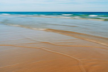 Yumuşak dalgalar kumlu sahilde yumuşak desenler yaratır. Bulanık hareket etkisine sahip..