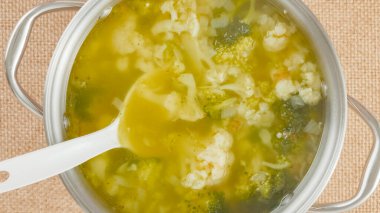 Cooking pot with cauliflower broccoli soup close-up on a table on a rustic background, view from above