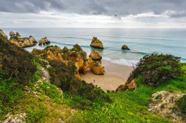 Doğal kemerleri ve mağaraları olan engebeli bir kıyı şeridi çarpan okyanus dalgaları dramatik bir sahile ve bulutlu bir gökyüzüne sahip. Algarve, Portekiz