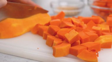 Tereyağlı kabak çorbası tarifi. Kadın balkabağı kesiyor. Mutfak masasının üzerinde çiğ sebzeler. Soyulmuş ve çekirdeksiz tereyağı ezmesi kesme tahtasına yakın plan.