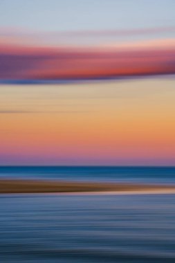 Okyanusun üzerinde yumuşak pembe ve mavi bulutlar olan renkli günbatımı gökyüzü.