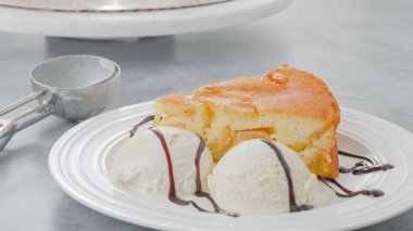 Slice of a freshly baked apple cake with whipped cream topping, served with vanilla ice cream and chocolate close-up on a white plate clipart