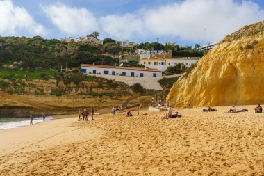 Algarve 'deki kumsalın tepesinde engebeli kayalıklar ve konut binaları var. Algarve, Portekiz, 2 Ocak 2024.  