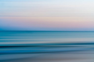 Okyanus ve pembe renkli bulutlu gökyüzü, soyut deniz manzarası, hareket bulanıklığı, günbatımı.