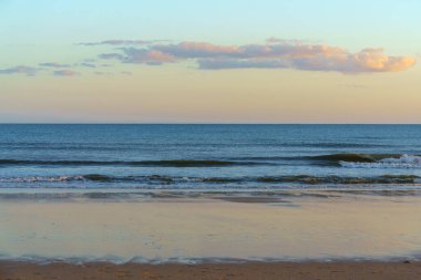 Yumuşak dalgalı huzurlu deniz manzarası ve gün batımında sakin bir ufuk..