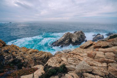 Kasvetli bir bulutlu günde Rocky plajı ve okyanus manzarası
