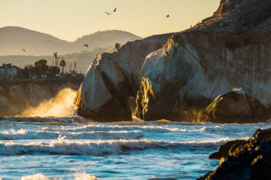 Okyanus dalgaları gün batımında kayalara çarpıyor Pismo Sahili, Kaliforniya merkez sahilinde dramatik deniz manzarası.