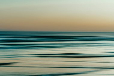 Sakin tonlarda alacakaranlık ışığını yansıtan yumuşak, bulanık dalgalar..