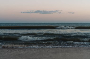 Sakin tonlarda alacakaranlık ışığını yansıtan yumuşak, bulanık dalgalar..