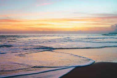 Güneş ufkun altına batıyor, nefes kesen günbatımında kumsalı altın rengine boyuyor.