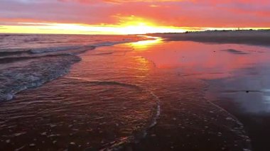 Altın gün batımı sakin kıyı şeridine yansıyor. Yüksek kalite 4k görüntü