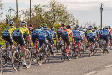 Tavira, Portekiz, 21 Şubat 2025. Bisikletçiler virajlı bir yolda bir peloton yarışına sıkıca sokuldular. Volta ao Algarve, yol bisikleti yarışı. Aşama 3, Tavira, Algarve.