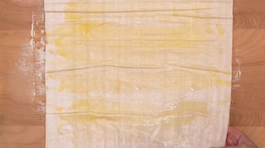 Phyllo hamur ve eritilmiş tereyağı yakın plan ahşap kaplama, pişirme işlemi. Yüksek kalite 4k görüntü