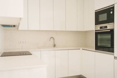 Entegre cihazlar ve minimalist dolaplar içeren gösterişli mutfak tasarımı.