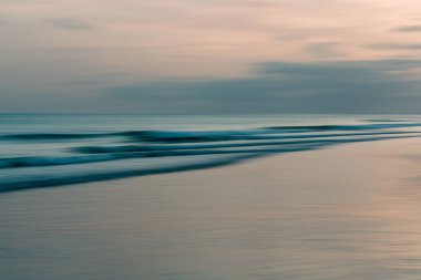 Yumuşak okyanus gelgitleri kararmış ufukta sessiz tonlarda harmanlanır..