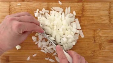 Beyaz soğanı ince ince doğrayan bir elle tahta kesme tahtasının üzerinde küçük şeritler halinde. Yüksek kalite 4k görüntü