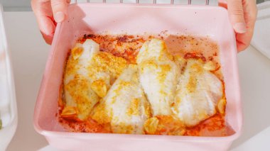 Pişmiş balık fileto pembe bir kabın içinde altın sarımsak çeşnili.