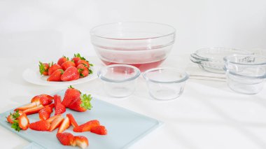 Cam kaseler ve mutfak tezgahında çilekli jöle tabanlı büyük bir karıştırma kabı..