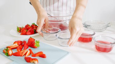 Eller cam kaseler dolusu çilek jölesini düzgün bir düzende yerleştiriyor..