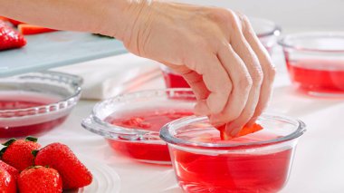 Dilimlenmiş çilekleri cam bir kase jöleye koymak..