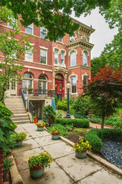 Ön bahçesi ve saksılı çiçekleri olan süslü tuğlalı bir ev sessiz bir yürüyüş yolu..