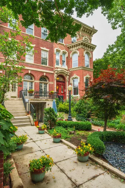 Ön bahçesi ve saksılı çiçekleri olan süslü tuğlalı bir ev sessiz bir yürüyüş yolu..