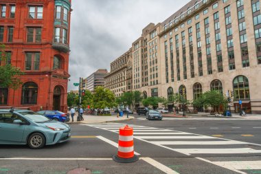 Washington D.C., ABD - 21 Mayıs 2025. Kırmızı tuğla bina ve modern cepheler de dahil olmak üzere zıt mimari tarzların kesişme görüntüsü.