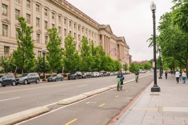 Washington D.C., ABD - 21 Mayıs 2025. Bisikletçiler, hükümet binaları ve Amerikan bayraklarıyla çevrili bir bisiklet yolu boyunca gidiyorlar..