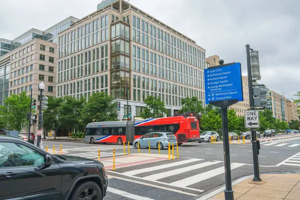 Washington D.C., ABD - 21 Mayıs 2025. Arabalar, otobüsler ve yüksek cam binalarla dolu bir kavşak..