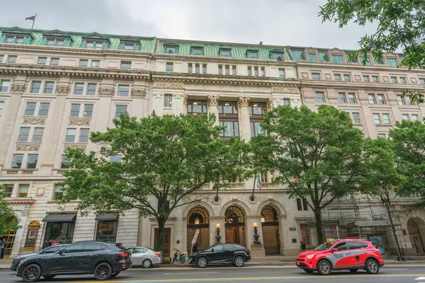 Washington D.C., ABD - 21 Mayıs 2025. Ağaçlar ve sokak trafiği tarafından çerçevelenmiş tarihi bir banka binasının şık cephesi.