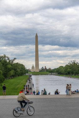 Washington D.C., ABD, - 23 Mayıs 2025, Bisikletçi Yansıyan Havuz 'dan geçiyor ve Washington Anıtı yükseliyor..