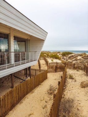 Durgun sahil restoranı, kumullara ve okyanusa bakıyor, tahta çitlerle çevrili..