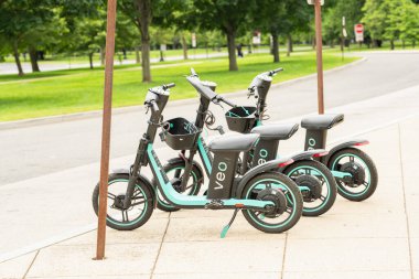 Washington D.C., ABD, 26 Mayıs 2025. Arka planda yemyeşil ağaçlar olan kaldırımda park halindeki Veo elektrikli bisikletleri.