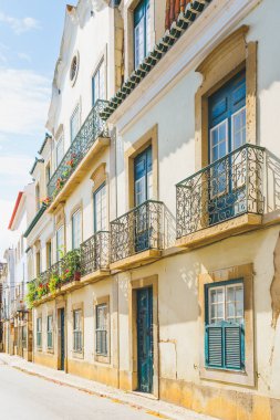 Dekoratif işlenmiş demir balkonlar renkli çiçekler ve tarihi bir Akdeniz binasının ön cephesinde saksı bitkileriyle dolup taşıyor..