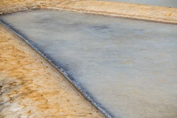 Geleneksel tuz düzlüklerinde buharlaşmanın ilk aşamalarında deniz suyuyla dolu tek bir tuz tavasına ayrıntılı bir bakış..