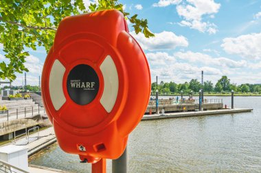 Washington D.C., ABD - 24 Mayıs 2025. Parlak turuncu bir can simidi Rıhtımdaki sakin nehir kenarına karşı duruyor..