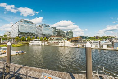 Washington D.C., ABD - 24 Mayıs 2025. Washington 'daki The Wharf' taki canlı marina lüks yatlar, yüzen rıhtımlar ve parlak mavi gökyüzü altında parlak modern binalar sergiliyor..