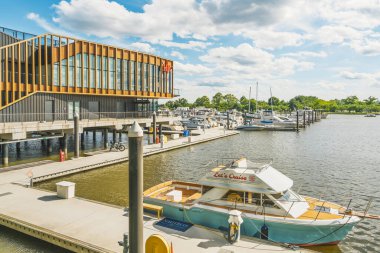 Washington D.C. - 24 Mayıs 2025. Lüks yatlar, yüzen yeşil adaları ve açık mavi gökyüzü olan modern bir marinaya demirlemiştir..