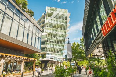 Washington D.C. - 24 Mayıs 2025. Yayalar, balkonları ve modern tasarımı olan çarpıcı yeşil cam bir binanın önünden geçiyorlar..