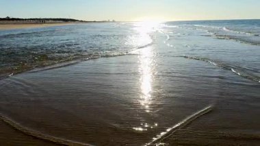 Yumuşak okyanus dalgaları açık bir gökyüzünün altında kıyıya doğru yuvarlanıyor. Yüksek kalite 4k görüntü