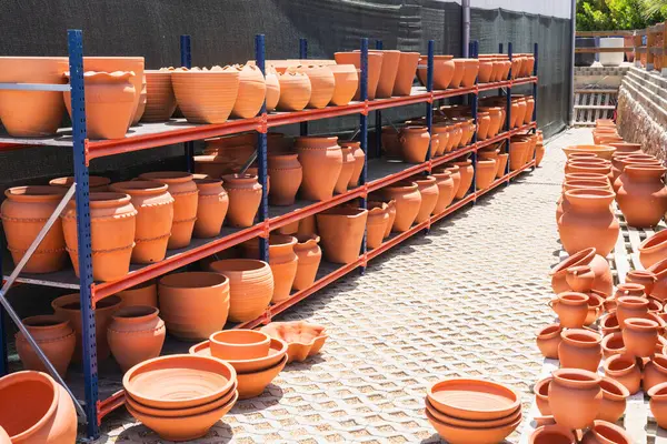 Bahçe merkezindeki metal raflardaki terasotta tencereleri.