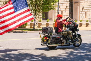 Washington D.C., ABD, 25 Mayıs 2025. Kırmızı Deniz Piyade Birliği ceketi giyen bir motorcu Anma Günü 'nde büyük bir Amerikan bayrağı taşıyor..
