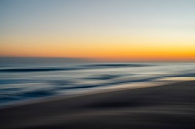 Okyanus dalgaları ve günbatımı renklerinin rüya gibi karışımı.
