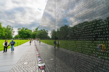 Washington D.C., ABD - 23 Mayıs 2025. Vietnam Gazileri Anıtı 'nın yansıtıcı siyah granit duvarı insanlar yakınlarda yürürken manzara boyunca uzanıyor..