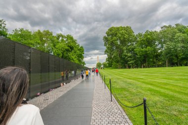 Washington D.C., ABD - 23 Mayıs 2025. Bulutlu bir günde Vietnam Gazileri Anıt Duvarı 'nın yanında yürüyen insanlar var..