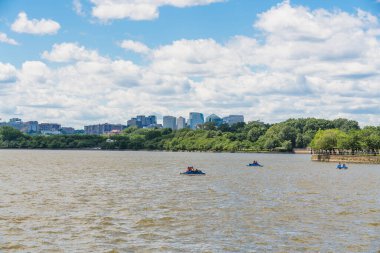 Washington D. C., USA - May 24, 2025. A distant view of paddle boats on the Tidal Basin with Arlington's skyline in the background.