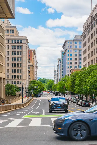 Washington D. C., USA - May 24, 2025. Cars drive through a central downtown street surrounded by government and commercial buildings.