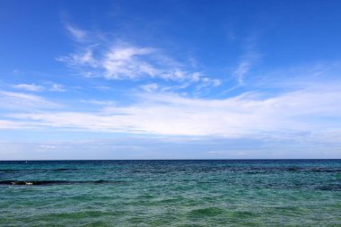 İtalya, Apulia 'da deniz kıyısında, zümrüt yeşili deniz suyu, mavi gökyüzü ve beyaz bulutlar. Tropik cennet kumsalı konsepti üzerine yaz tatili. Su sıçraması dalgası. Yaz titreşimleri.